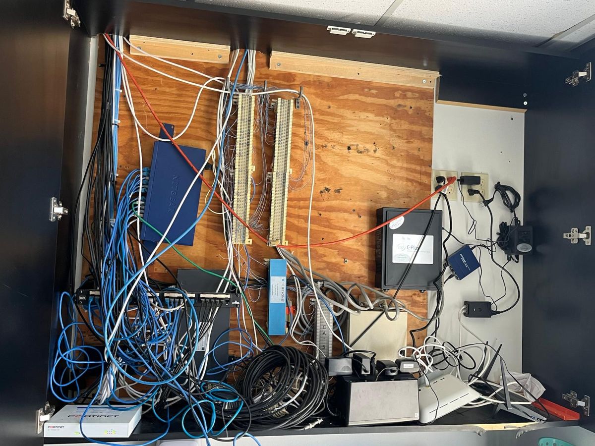 Network cabinet before: tangled, unmanaged cables